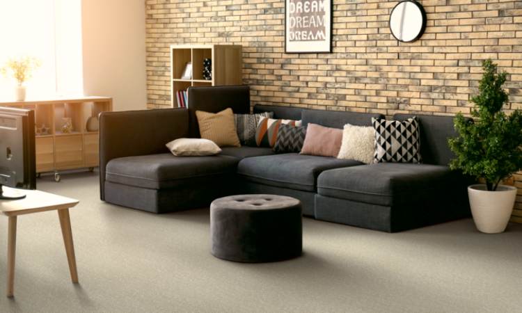 grey beige carpet in living room with blue couch and brick wall